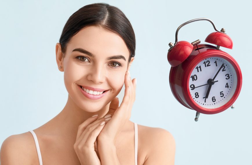 Mujer sonriente junto a un reloj despertador, simbolizando la importancia del tiempo en la vitrificación y congelación de gametos y embriones.