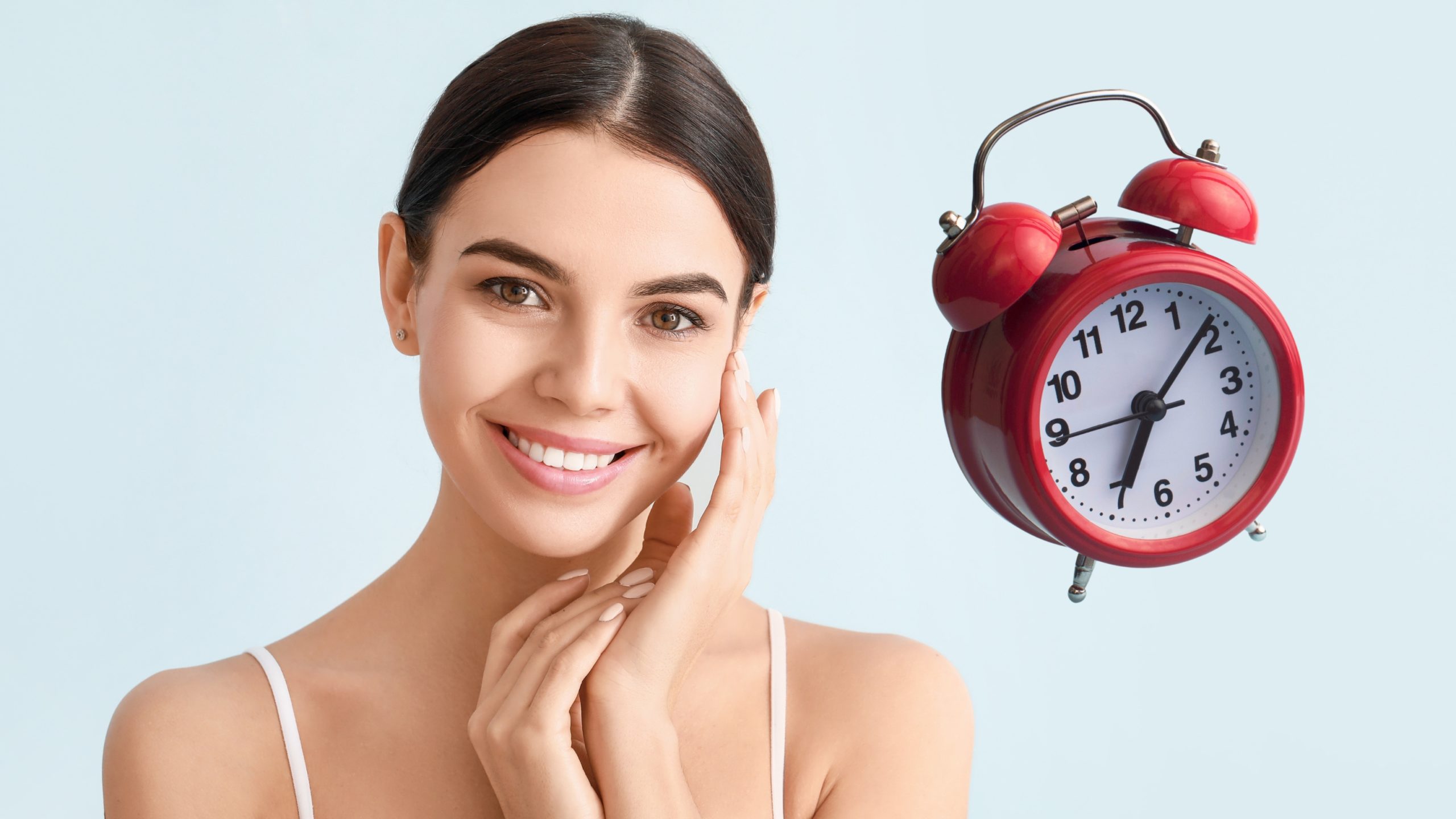 Mujer sonriente junto a un reloj despertador, simbolizando la importancia del tiempo en la vitrificación y congelación de gametos y embriones.