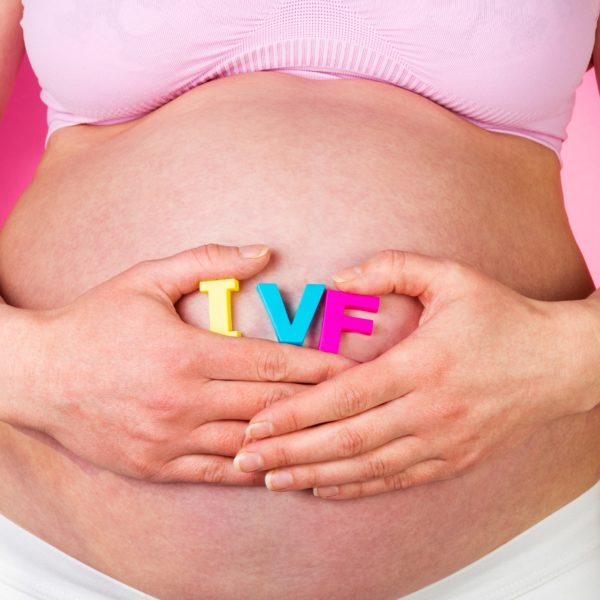 Vientre de mujer embarazada con letras “IVF”, representando un embarazo por fecundación in vitro con óvulos donados