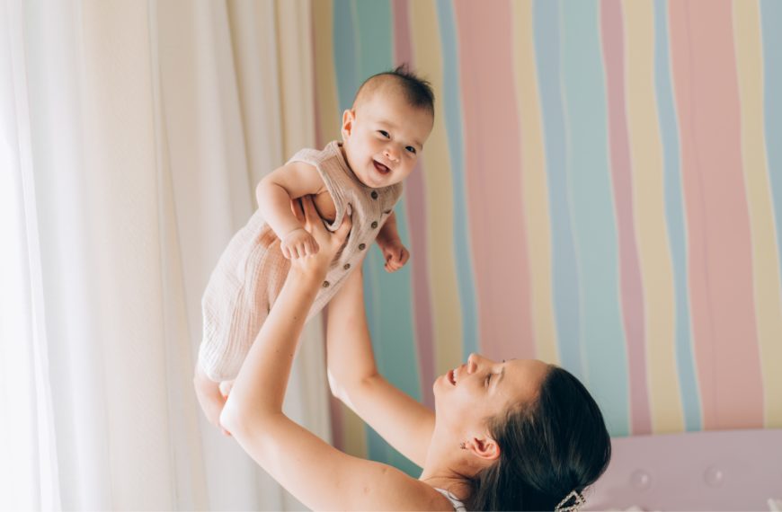 Madre levantando a su bebé con felicidad, representando el éxito de los tratamientos de fertilidad y reproducción asistida.